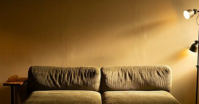 Oświetlenie salonu na jesienne wieczory – jak zaplanować światło warstwowe Sofa z lampą podłogową i stolikiem w salonie – ciepłe, warstwowe oświetlenie salonu