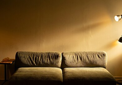 Oświetlenie salonu na jesienne wieczory – jak zaplanować światło warstwowe Sofa z lampą podłogową i stolikiem w salonie – ciepłe, warstwowe oświetlenie salonu